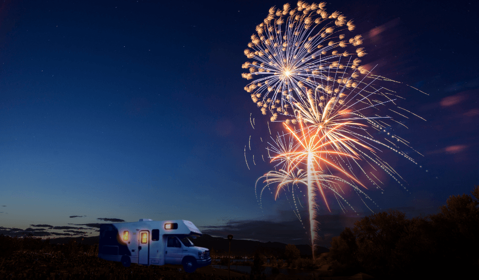 An RV under a dark fireworks-lit sky